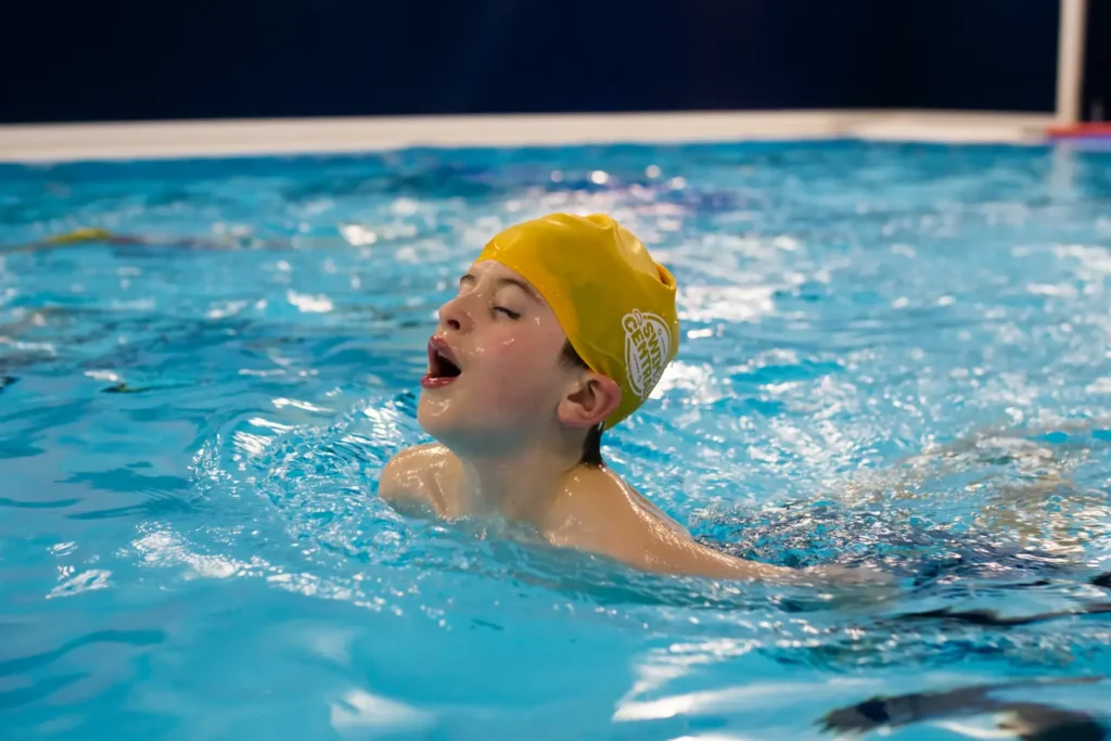 A young boy swimming in a butterfly stroke with his head out of the water