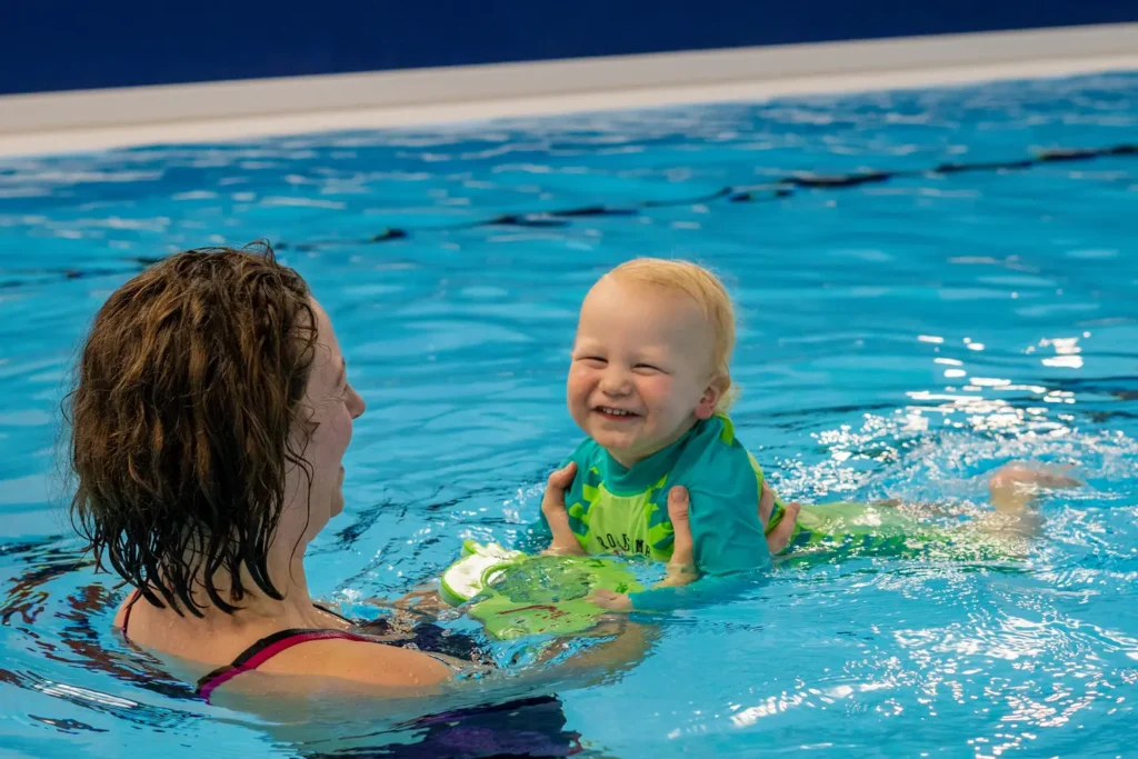 A very happy little baby with her smiling mum enjoying the warm pool