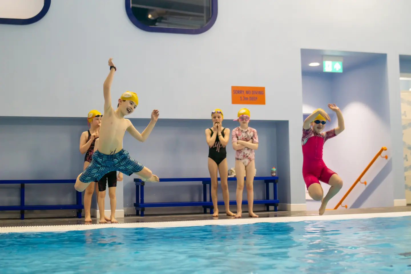 Two happy kids jumping into the pool at the same time
