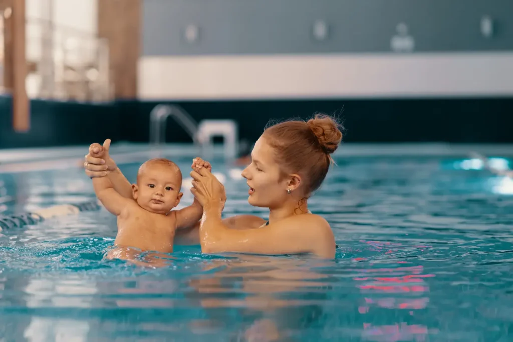 A young mother holding her baby's arms up in the water having fun