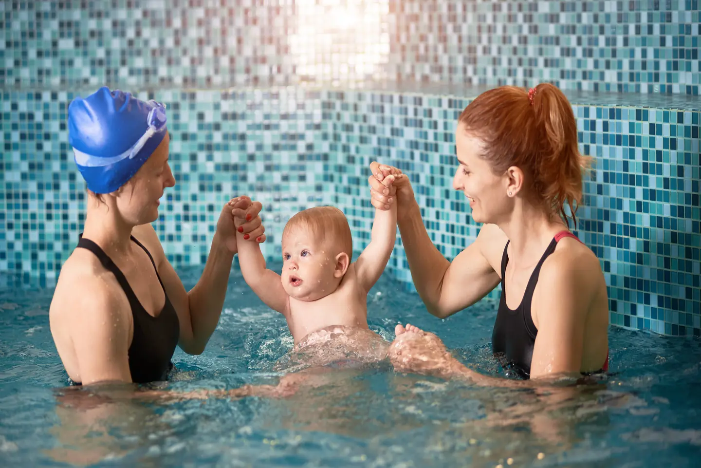 A swimming instructor and parent helping their baby to get comfortable with the water