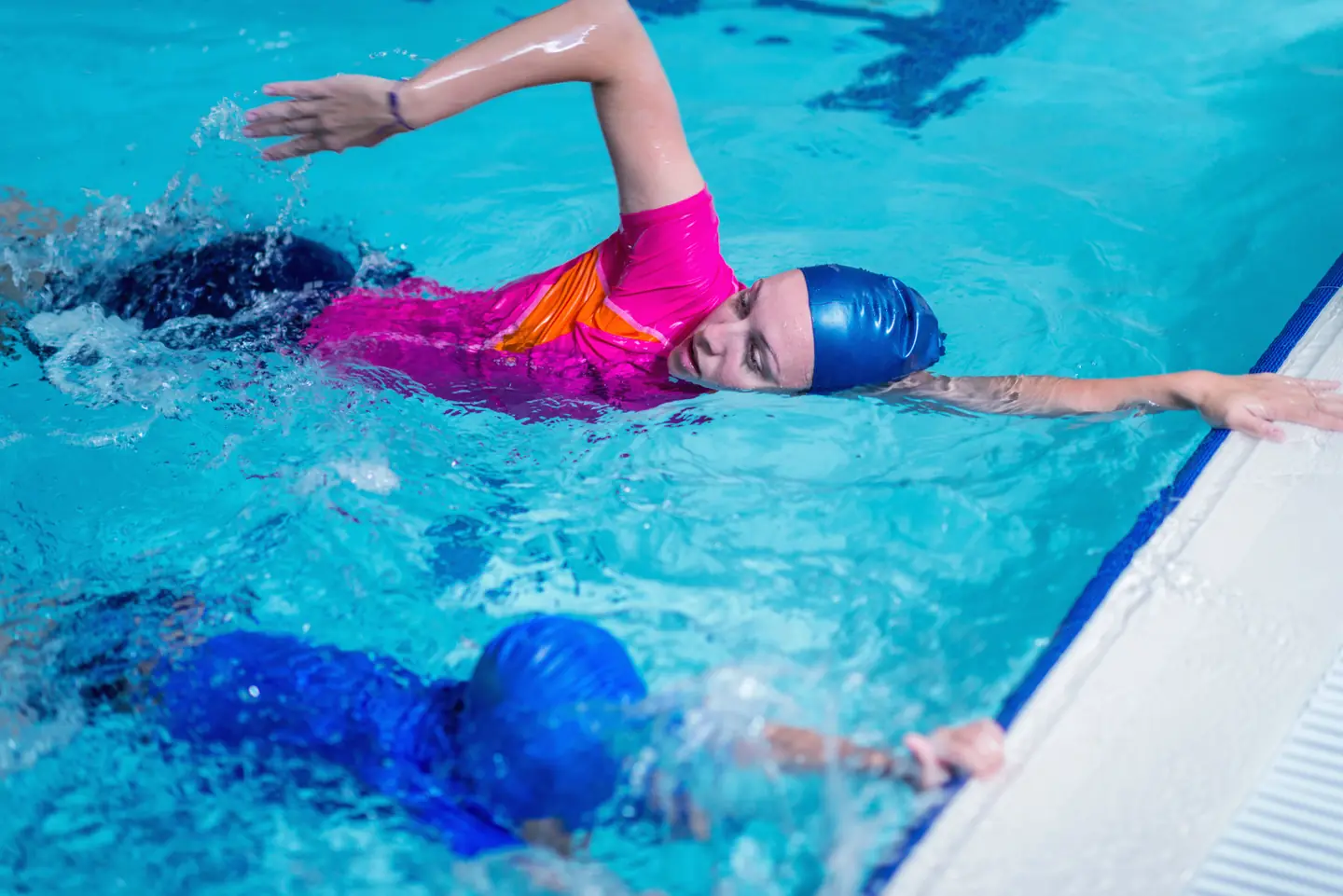 Swimming instructor teaching little boy how to kick his legs when swimming