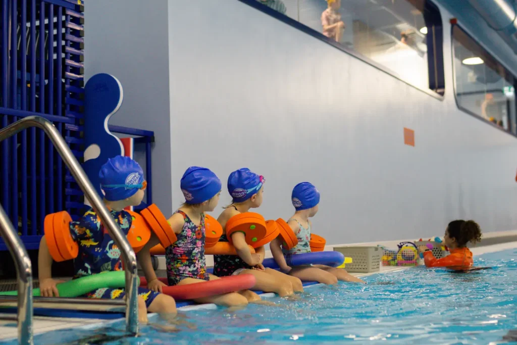 Swimming instructor handing out fun swimming toys to kids in her swimming class
